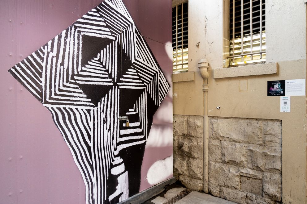 A black and white artwork on a pink background in the corner of an alley