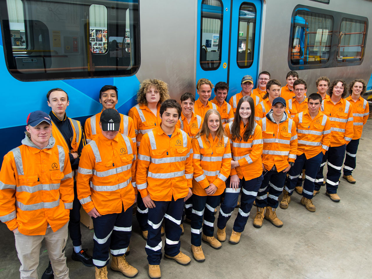 A large group of high school students standing in front of a train.