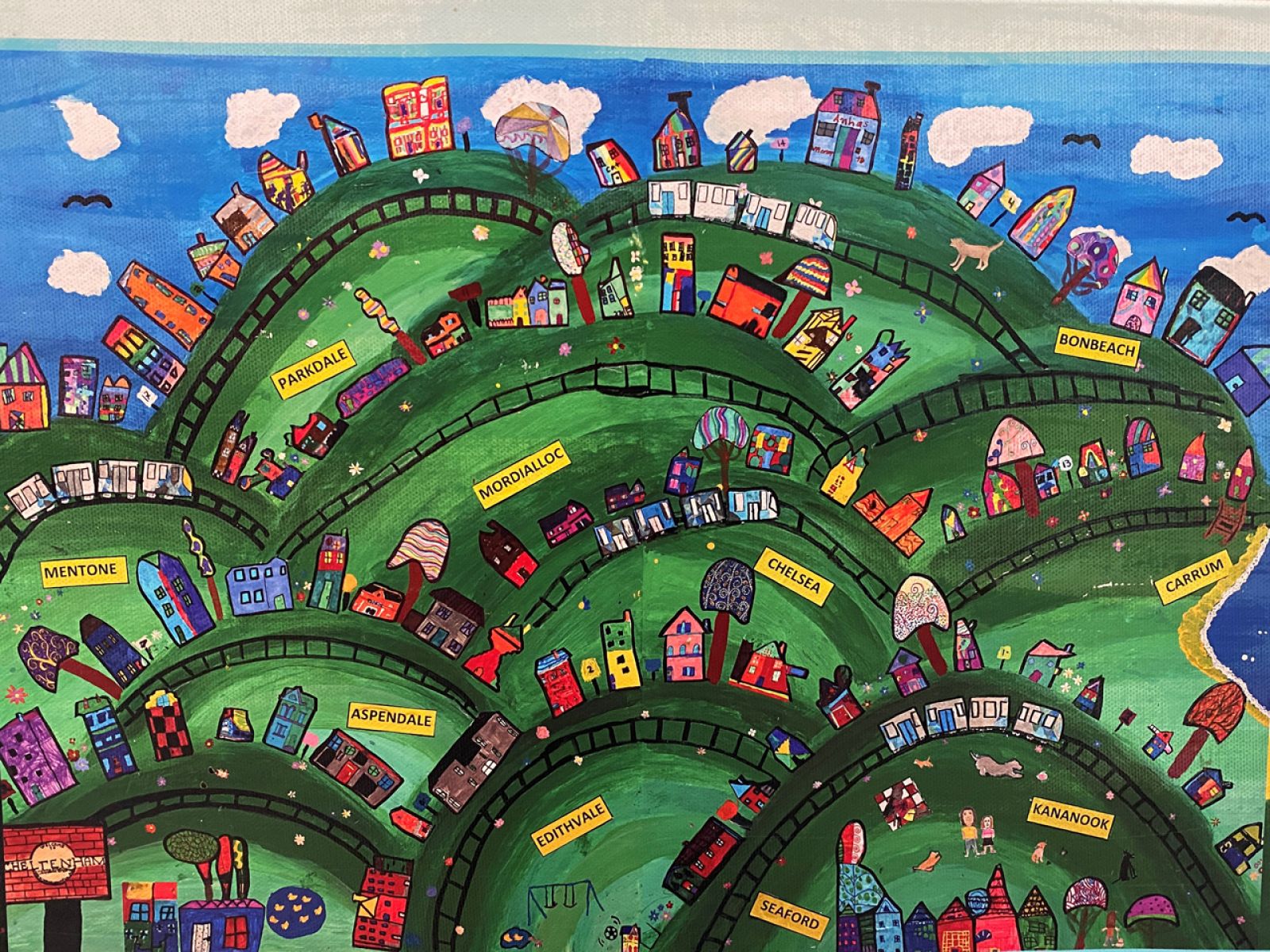 Painting showing houses and train tracks on green hills.