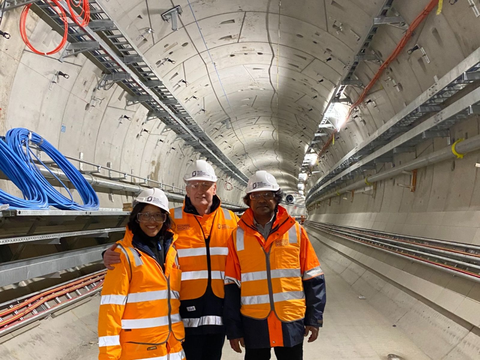 1 female and 2 male rail signalling engineers posing for a photo inside the Metro Tunnel