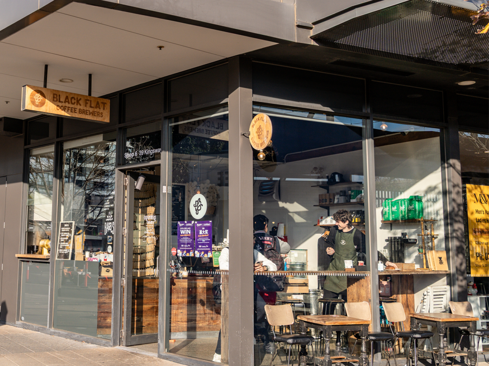 This image shows the the store front of Black Flat cafe with customers inside.