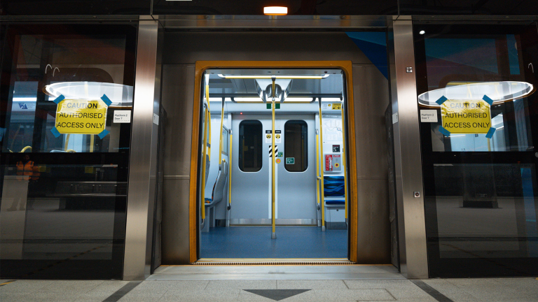 A train at a Metro Tunnel station with open doors and the platform screen doors open in front