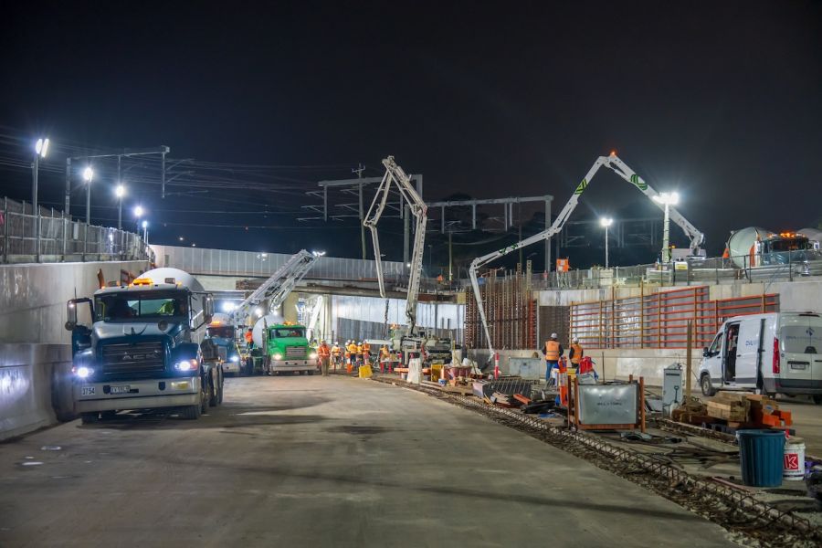 Concrete trucks delivering concrete for the underpass base slab pour beneath the rail bridge