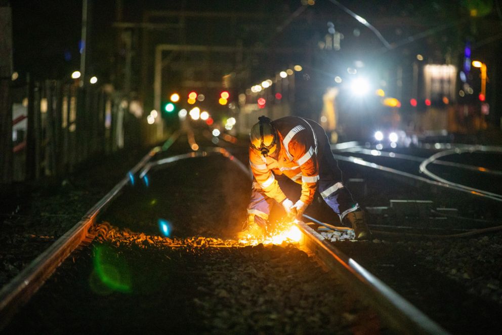 A worker cutting tracks at night