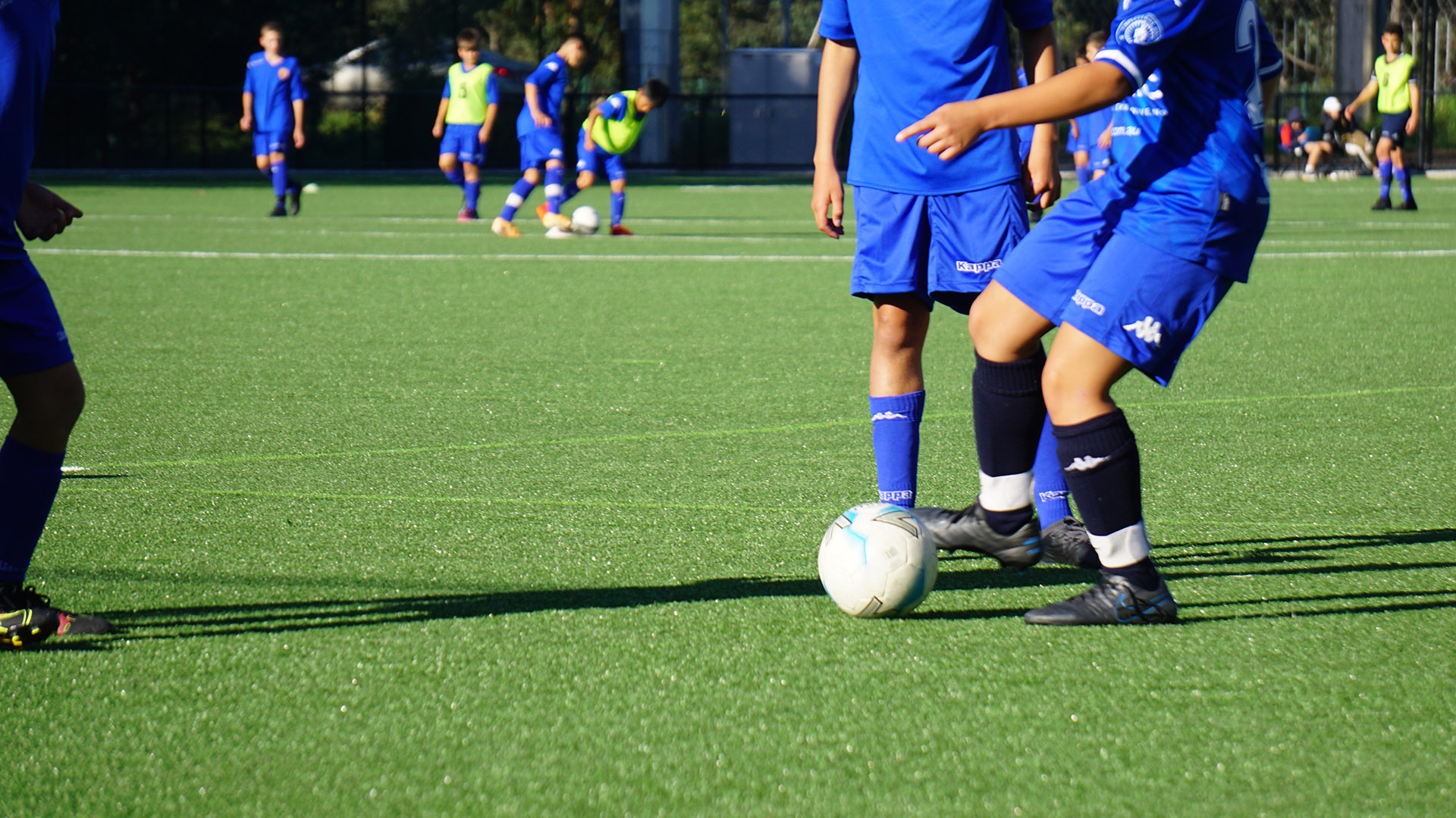 A group of soccer players wearing uniforms kicking a ball on a sports field.