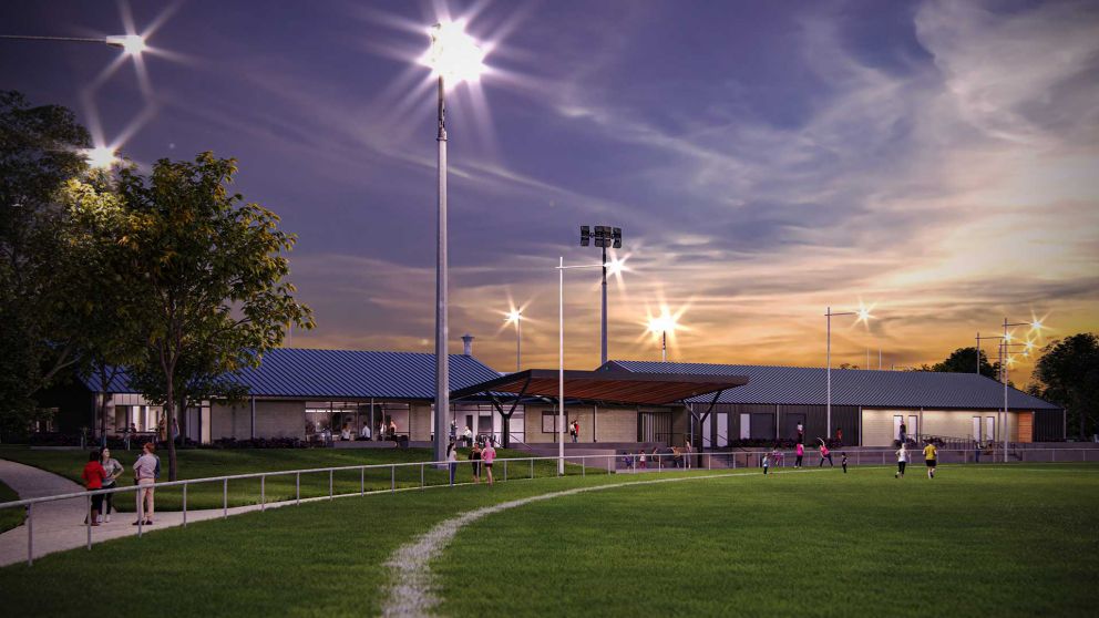 Artist impression of Ford Park oval and pavilion at dusk. People are playing soccer and exercising on the oval and floodlights shine on the oval. There are people inside a pavilion which overlooks the oval. 