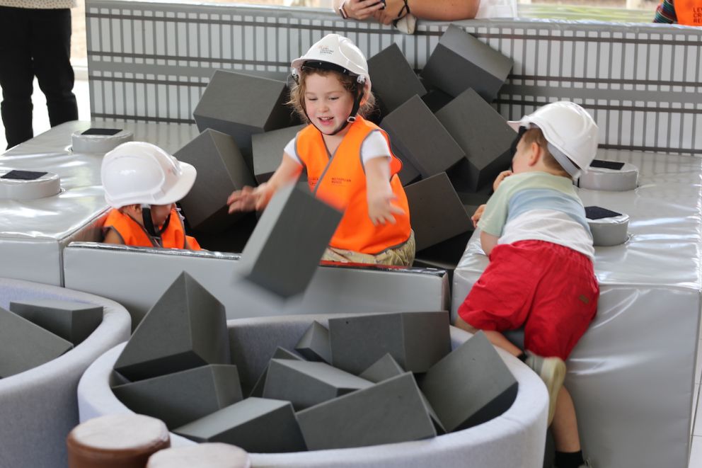 Three children wearing hi-vis playing with foam blocks.