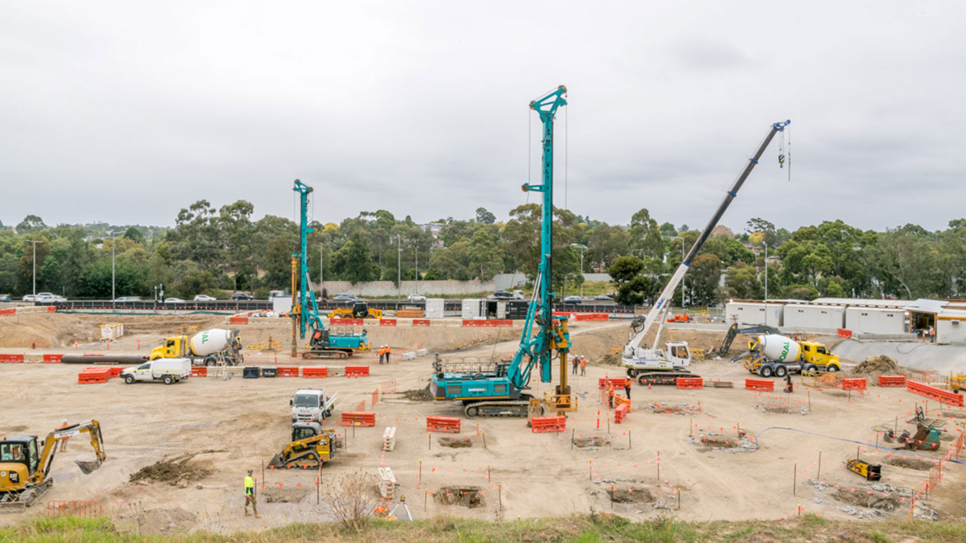An aerial view of a construction site with large cranes, machinery and construction workers.