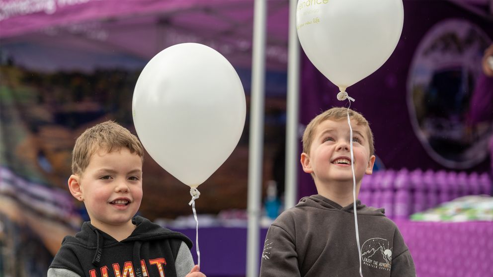 Two young kids holding balloons