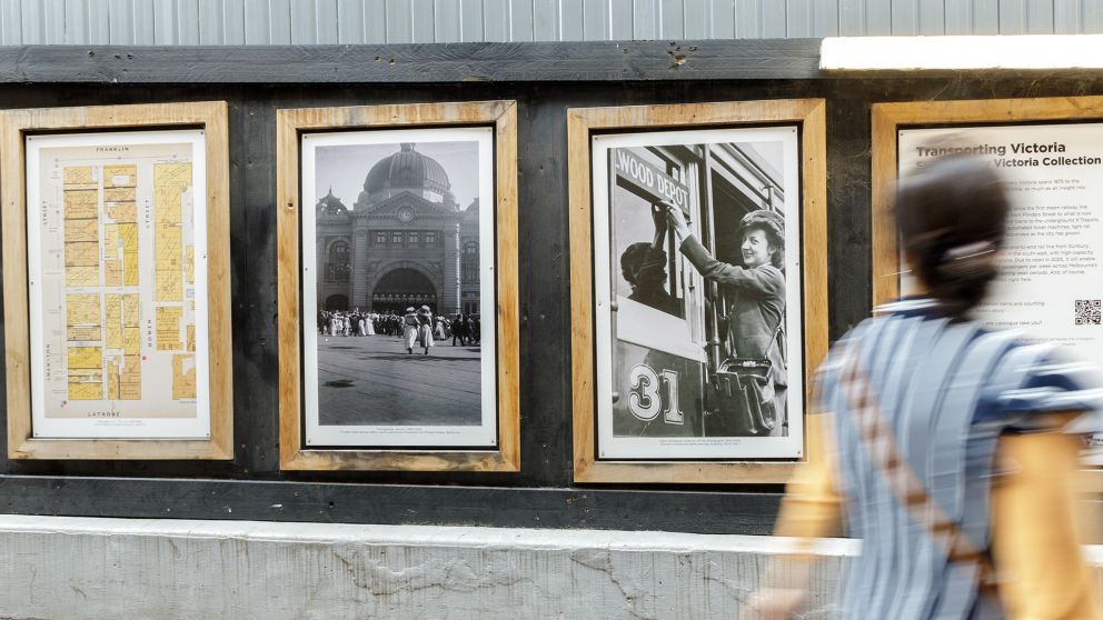 A person walks past old photographs on display in wooden frames
