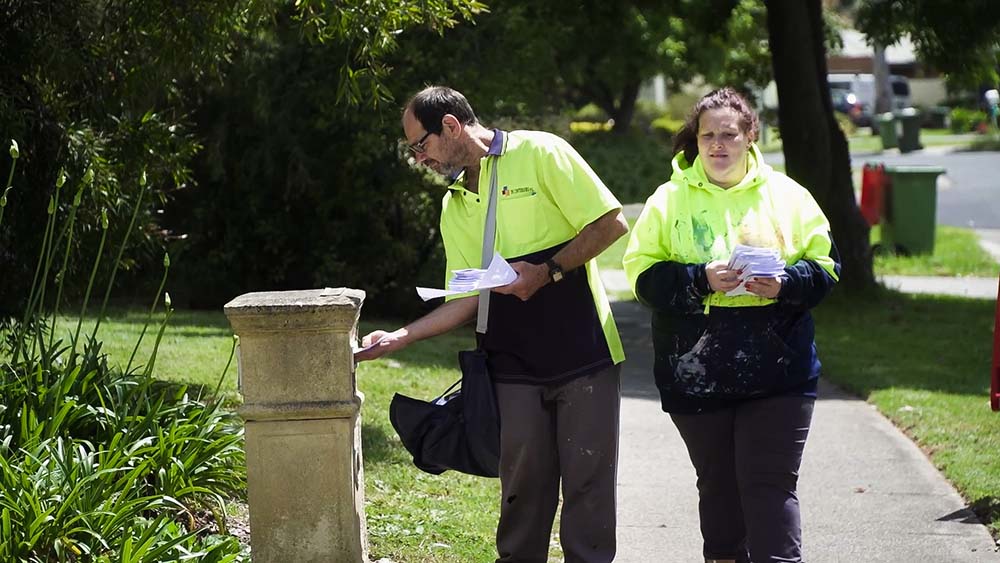 A man and woman delivering pamphlets