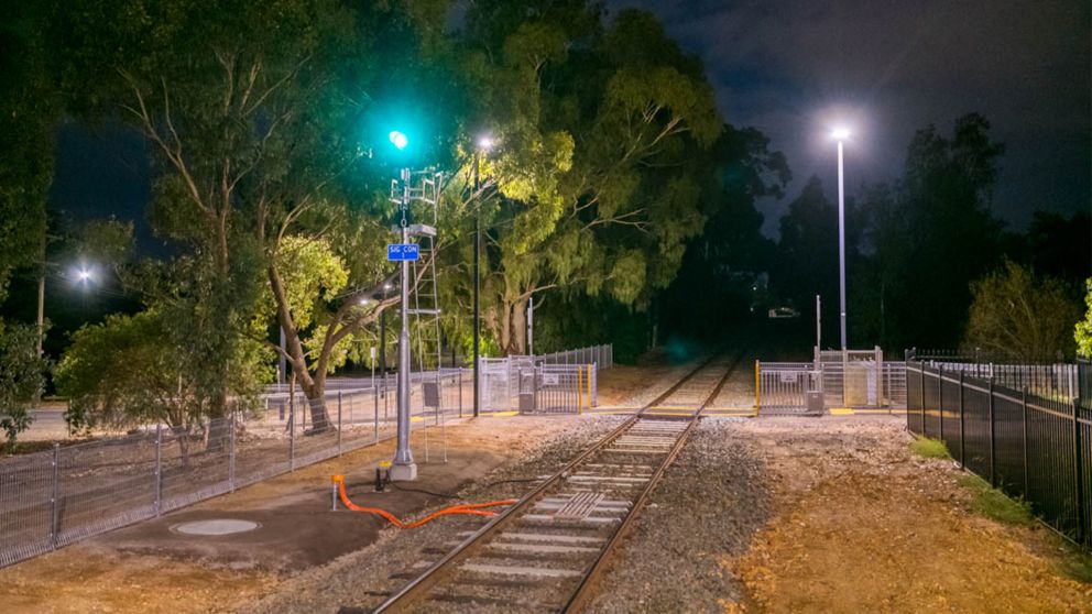 Eaglehawk Station signalling lit up with a green light and market street pedestrian crossing in the background at dawn as the sun is about to rise