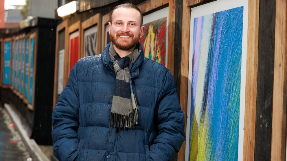Image of Rhys Cousins in front of his artwork in Franklin Street frames.