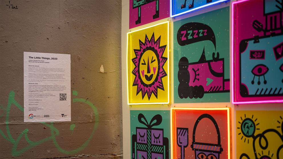 Close-up of an artwork featuring black line illustrations and neon lighting. Illustrations include a bright sun, a person sleeping and presents.