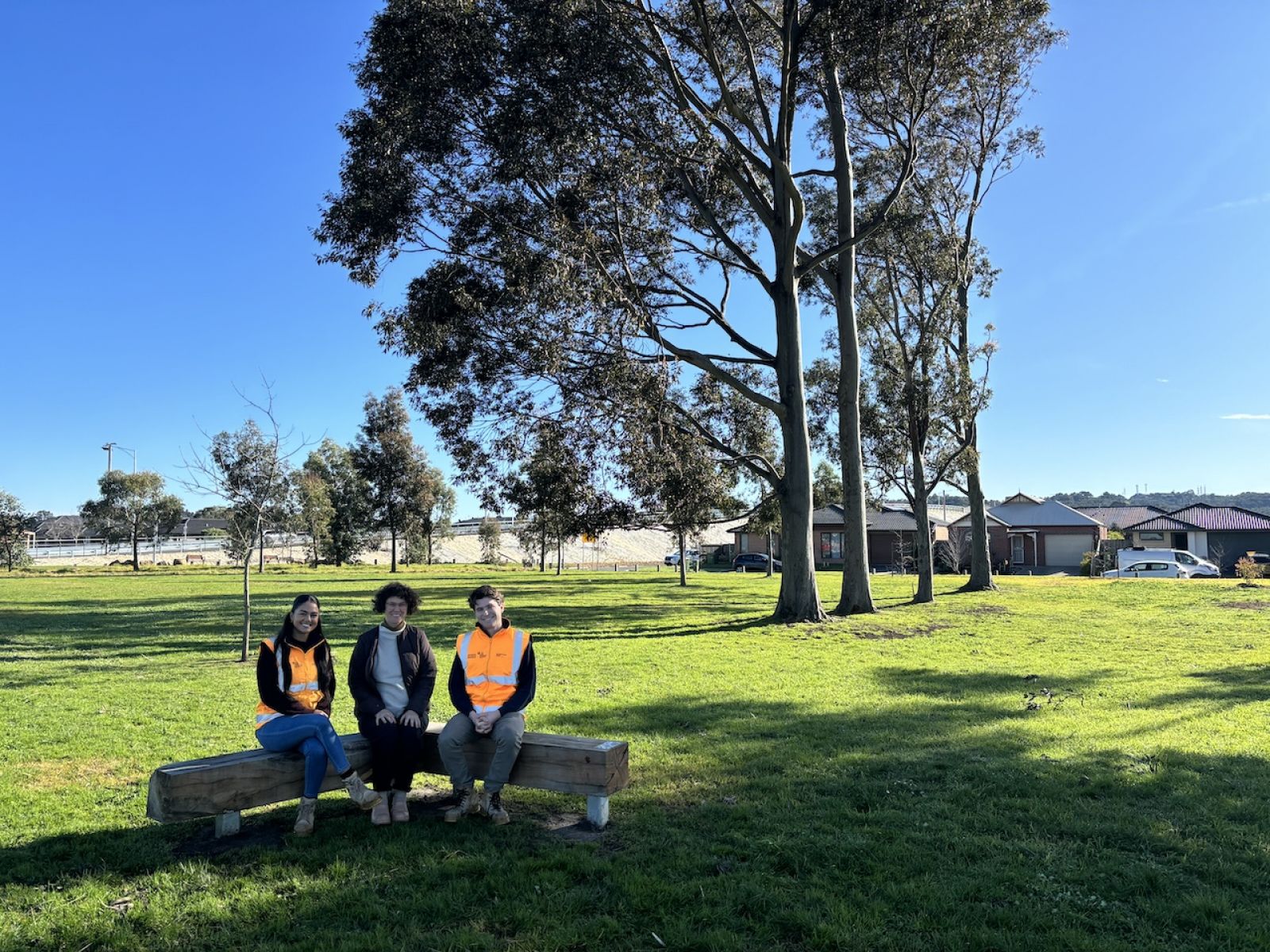 Three people sitting on the new park bench.