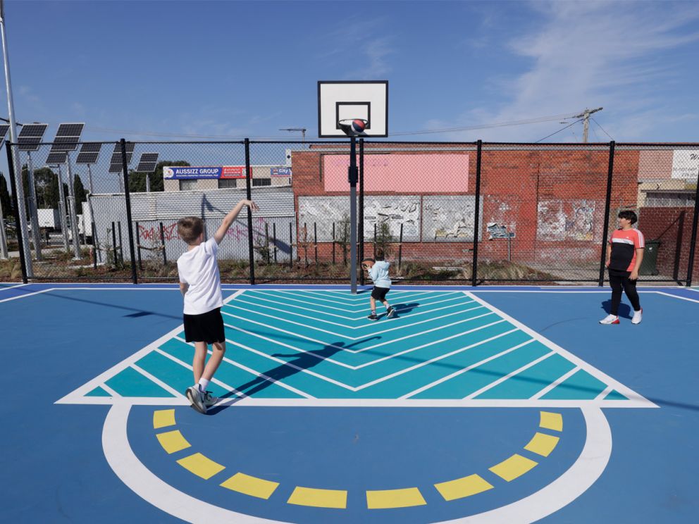A child shooting a basket ball at a newly constructed court.