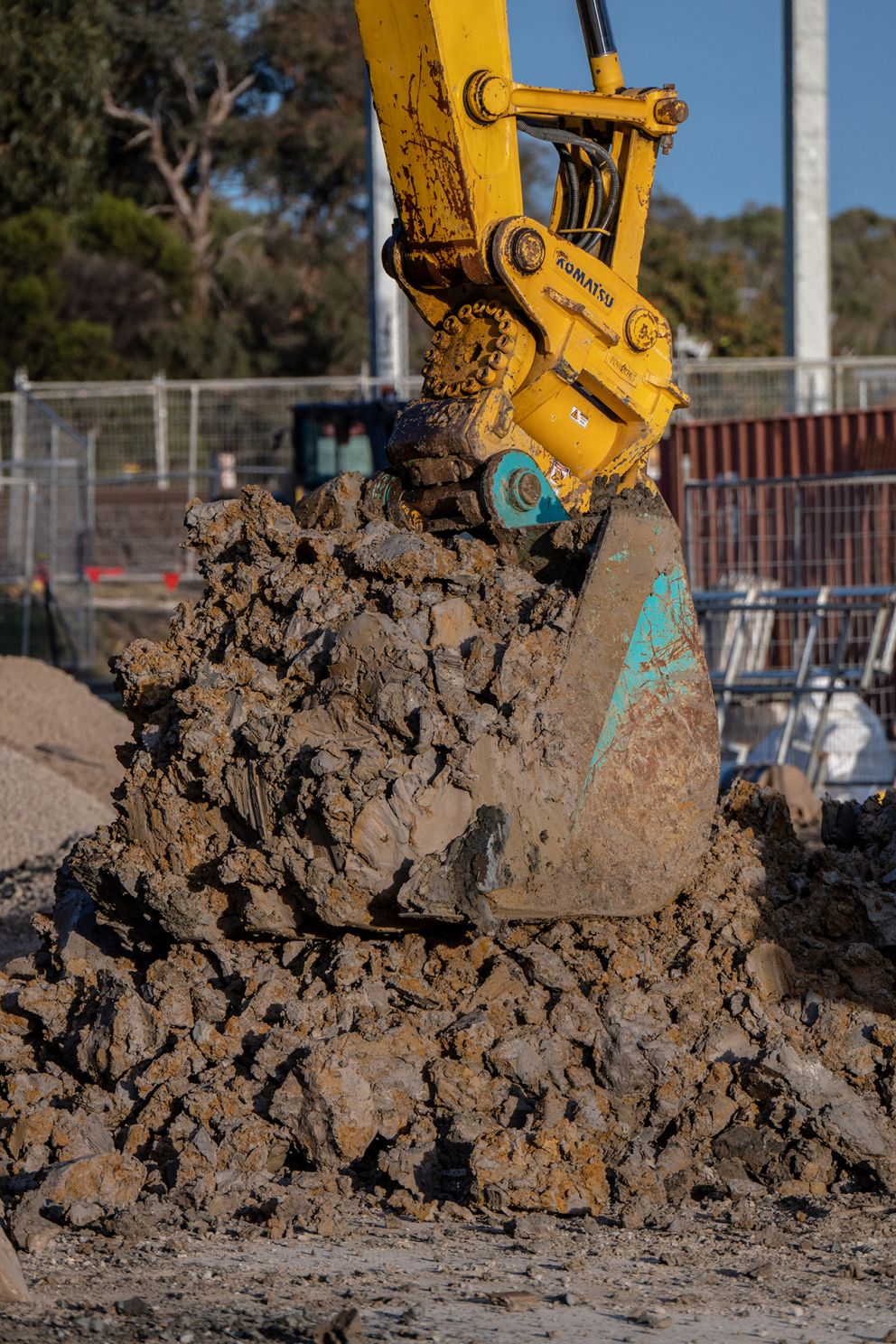 A digger moves soil that has been drilled up from piling works