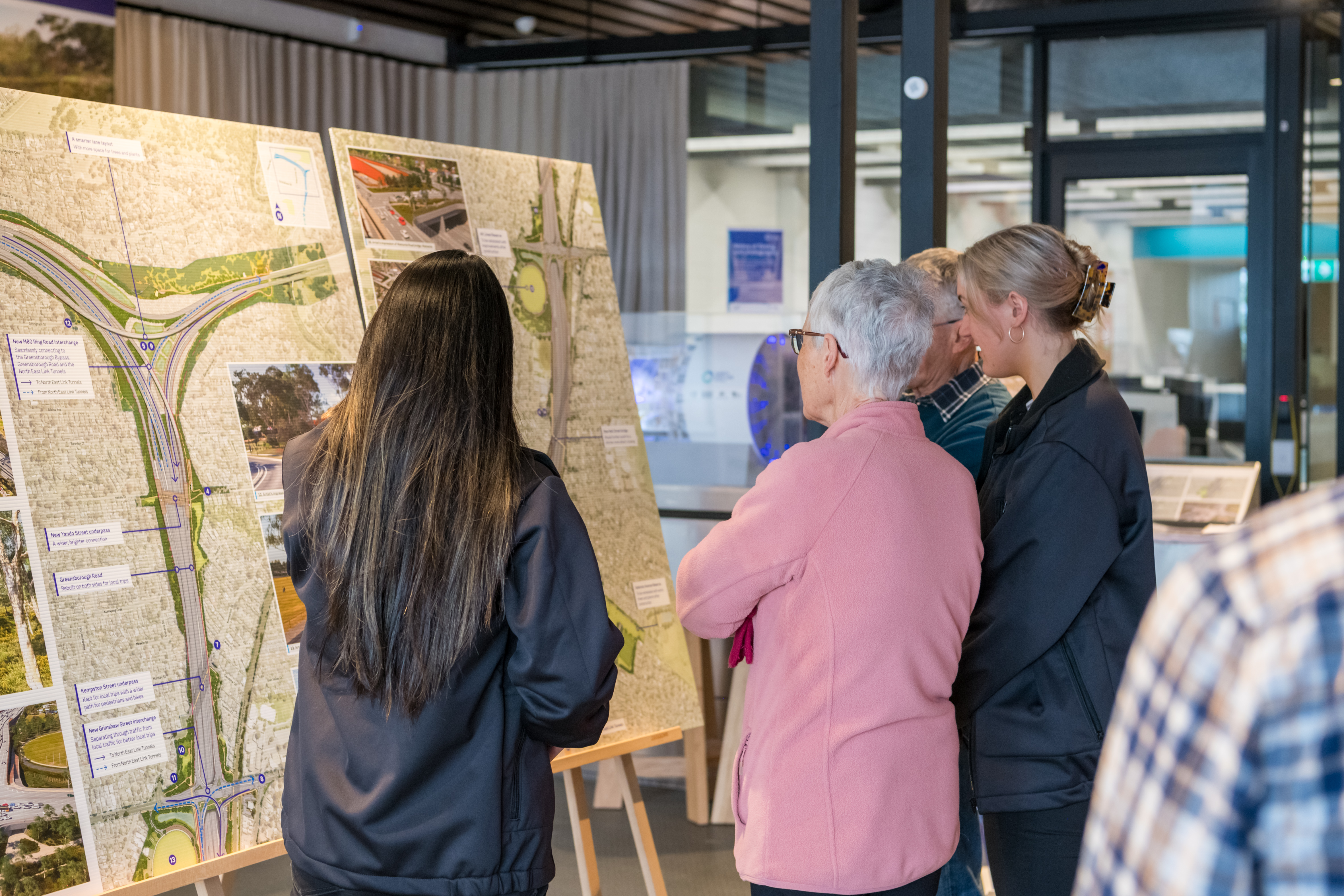 Crowd standing inside and looking at plans