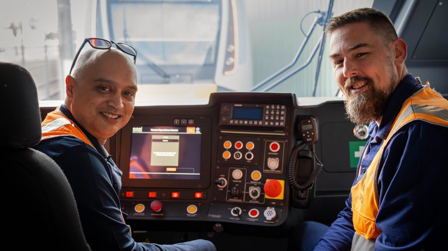 Two drivers sit in the cabin of an HCMT train. 