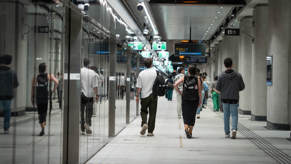 Passengers walk along the platform alongside the platform screen doors