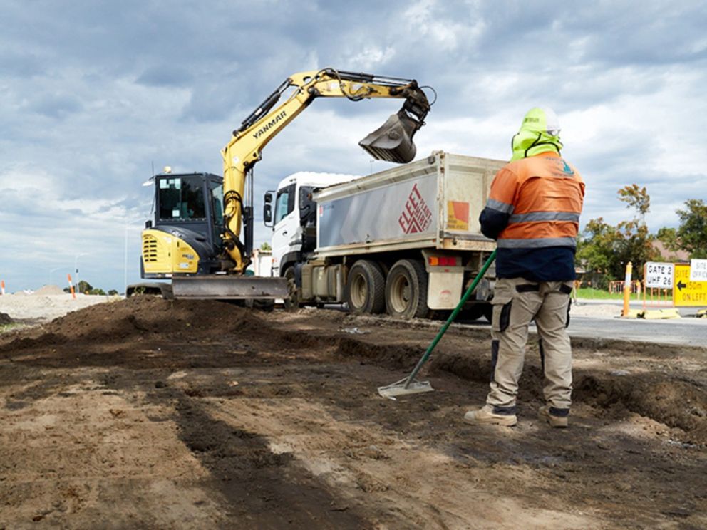 Image of a worker and excavator flattening earth for the roads