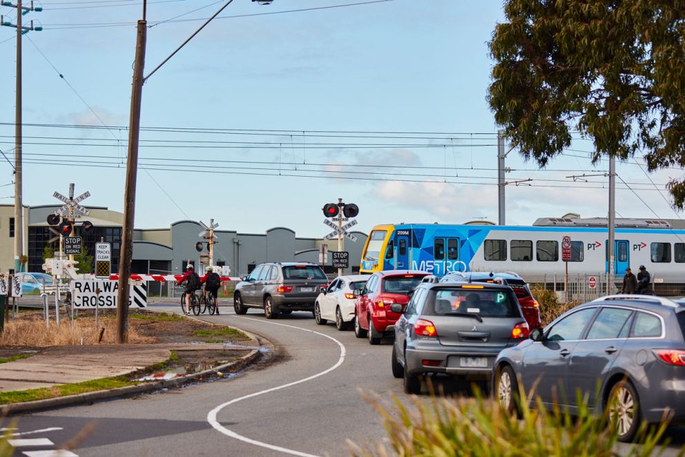 Traffic waiting at the Champion Road level crossing as a train is passing through