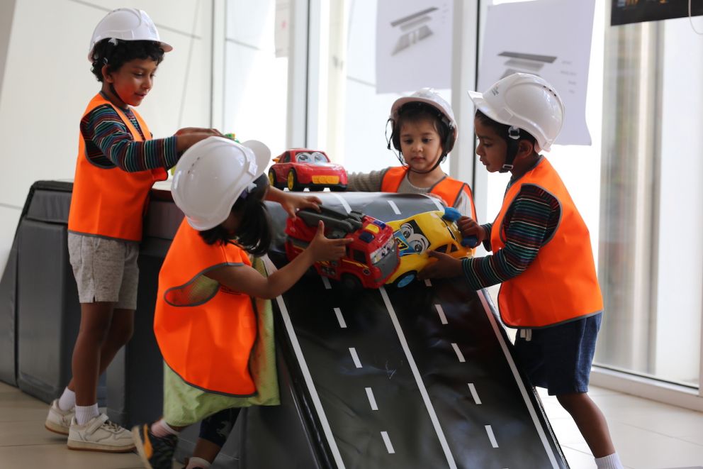 Four children playing with cars on a race track.