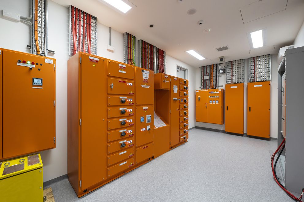 A room with several large orange control boxes and lots of wires coming out of them