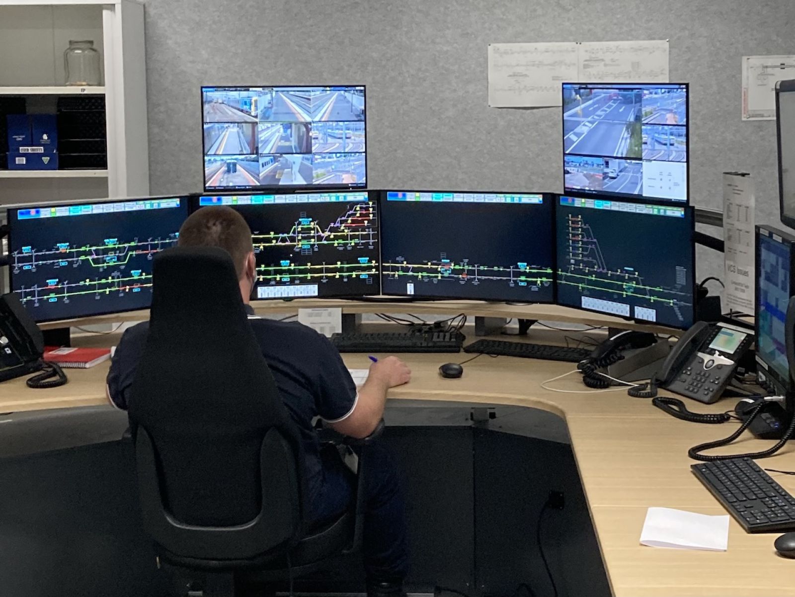 A worker watching multiple computer screens, observing the train network and signals.
