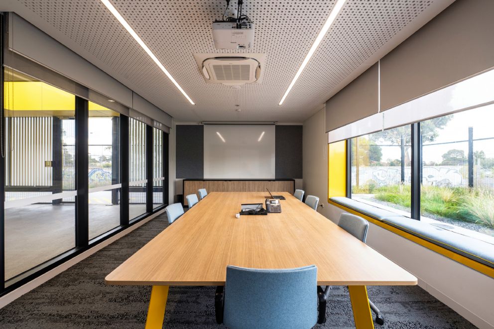 Interior of office with a wooden board room table with plants visible outside the window