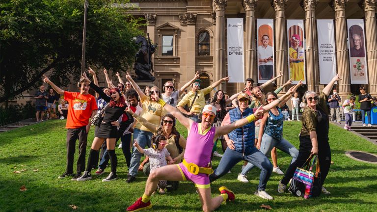 A group of people pose in front of the steps of the State Library