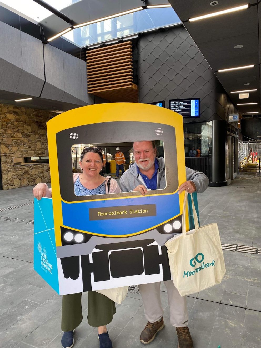 A lady and man stand behind a cardboard train cutout.