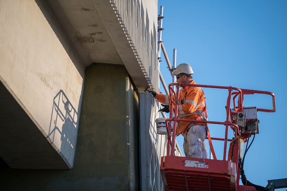 A construction worker paints the bridge during the construction blitz