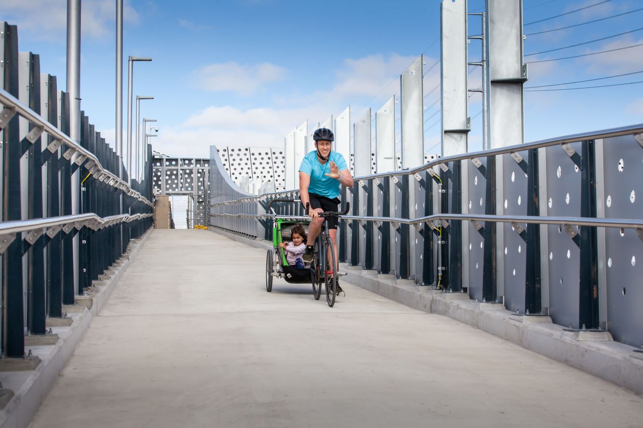 A cyclist and child riding across the new pedestrian bridge.