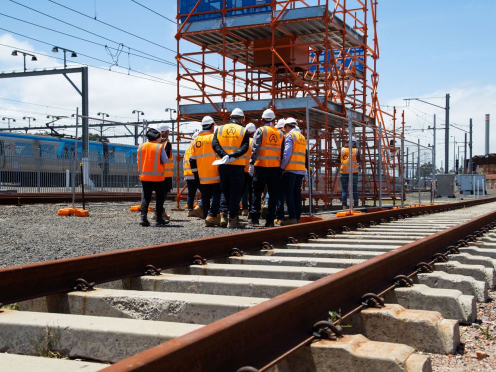 A group of people standing on training tracks at the Rail Academy.