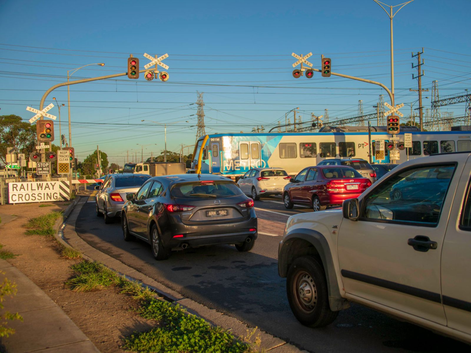 Cars waiting at Keon Parade level crossing as a train passes through