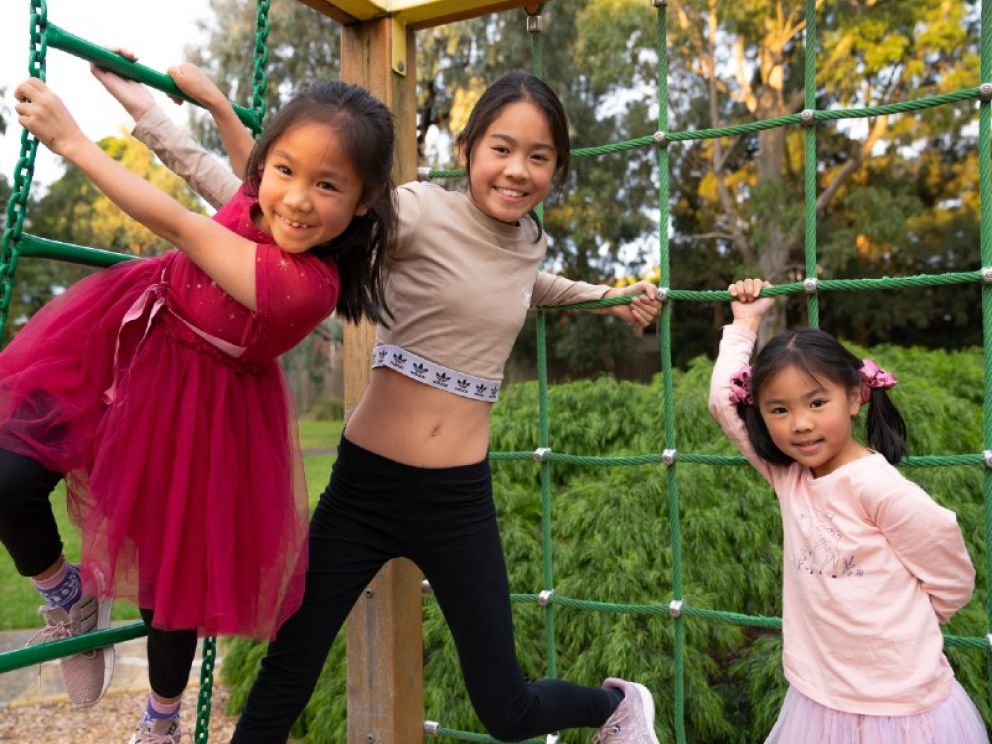 Three children climbing playground area