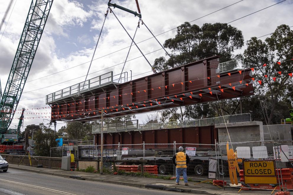 Crane lifting a section of the new Plenty River rail bridge into place